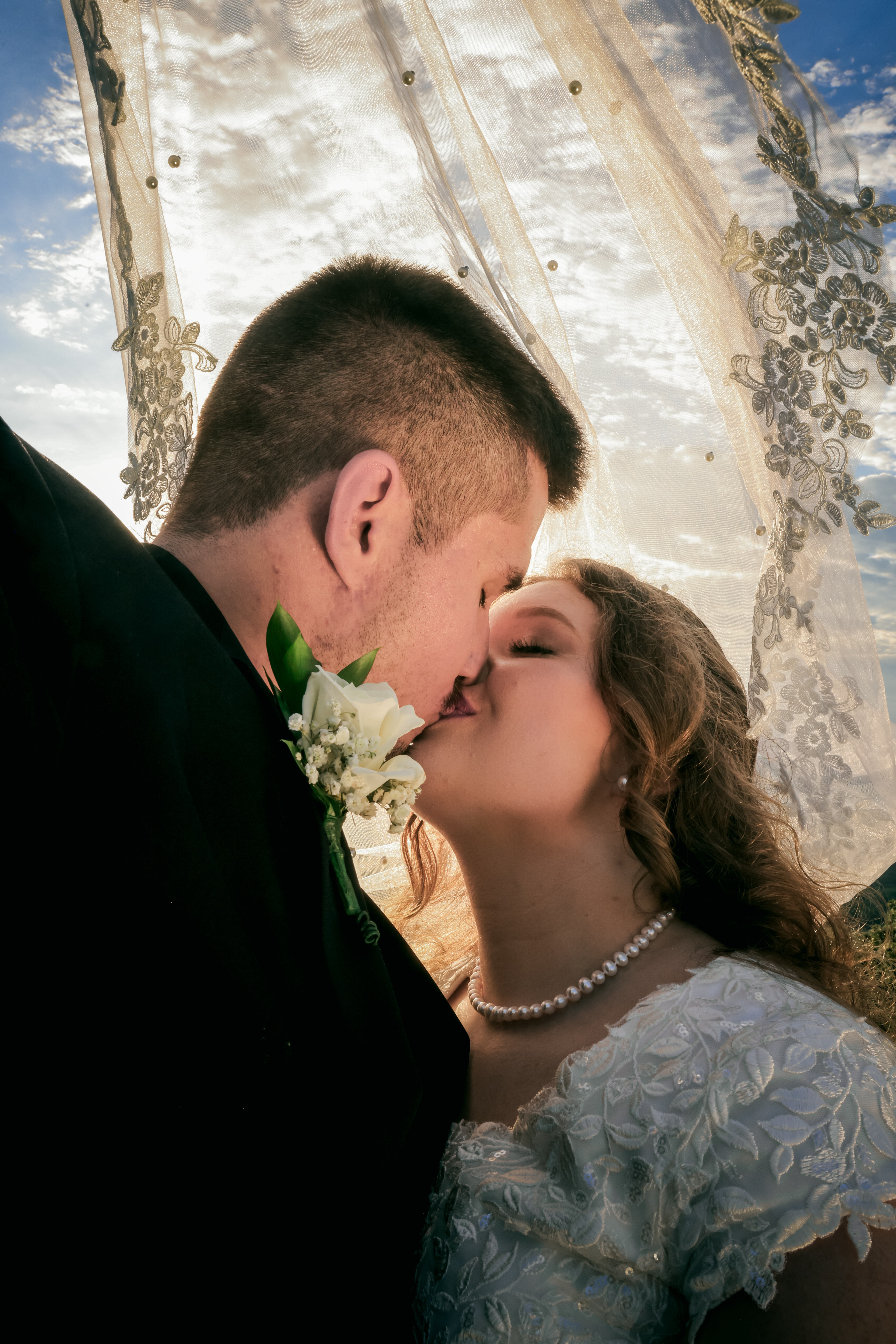 Bride and groom first kiss under lace arch